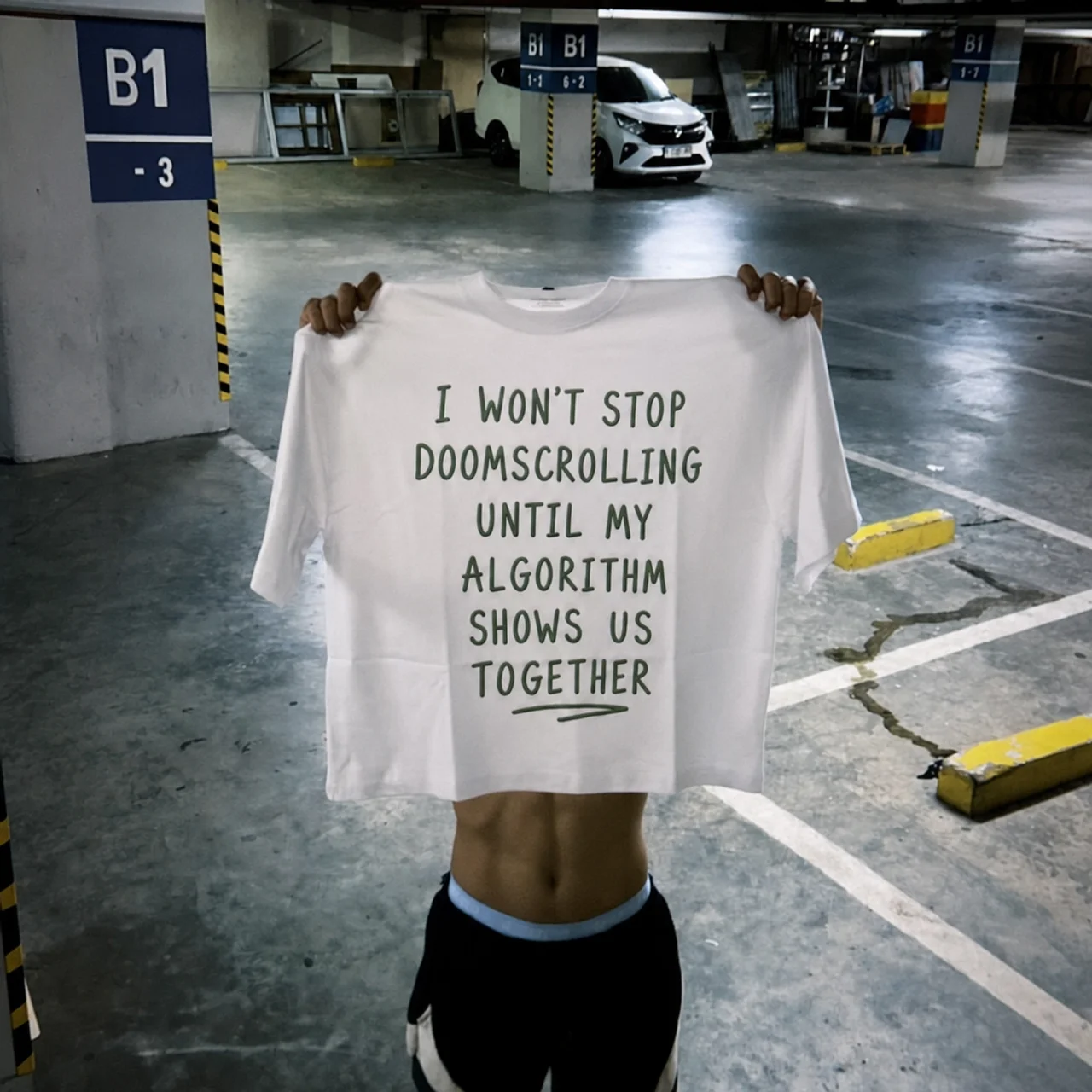 Doomscroll 'Away' Tee held up in a car park